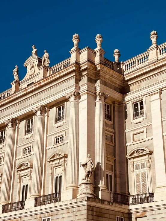 a large white building with a clock and people outside