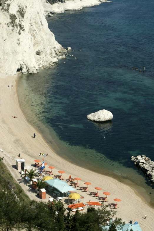 a view of a beach with umbrellas and some rocks in the water