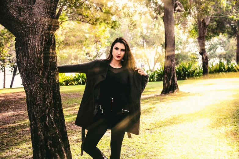 an attractive young woman posing next to a tree