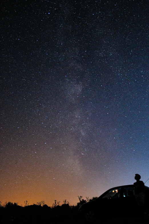 a group of people sitting on top of a hill at night under the stars