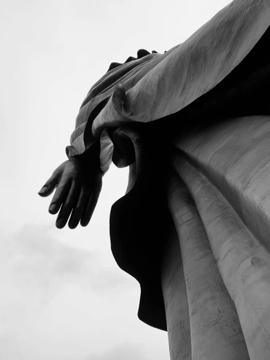 a statue in black and white with clouds in the background