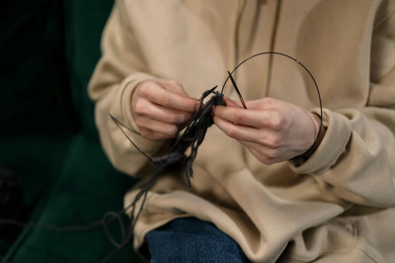 a woman is holding a plant stem and yarn