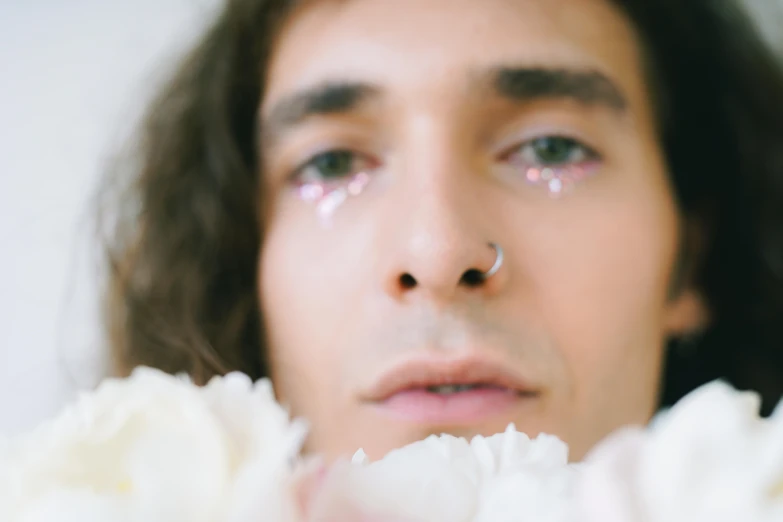 close up of man staring at camera holding a flower