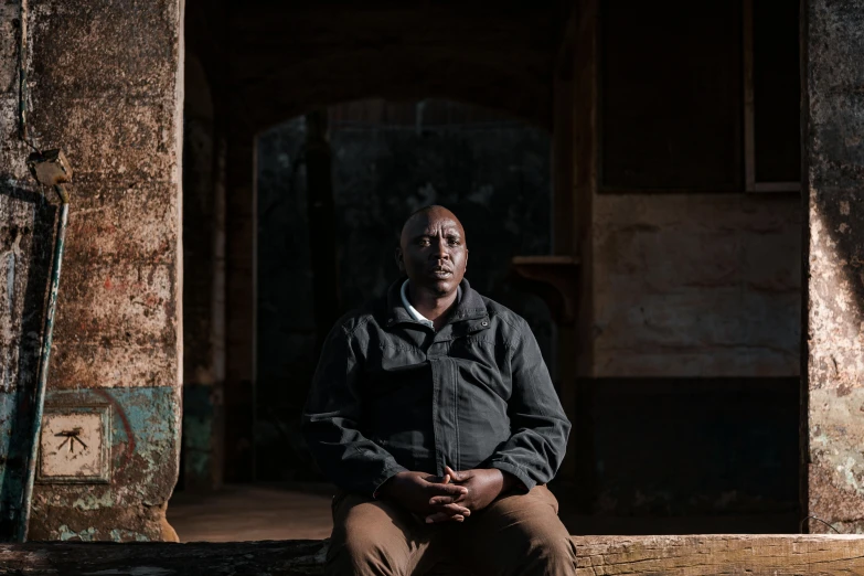 a man sitting on a wooden bench in front of an old building