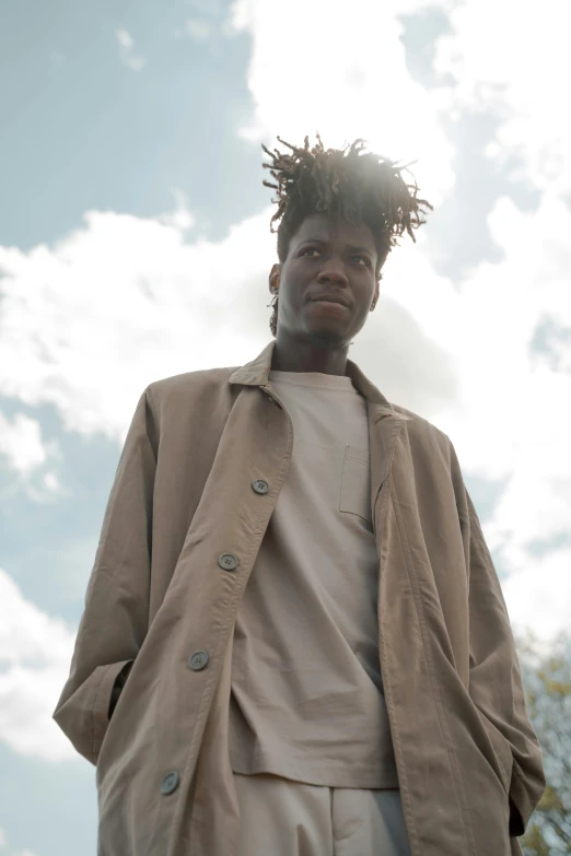 an african american man is standing under a bright cloud filled sky