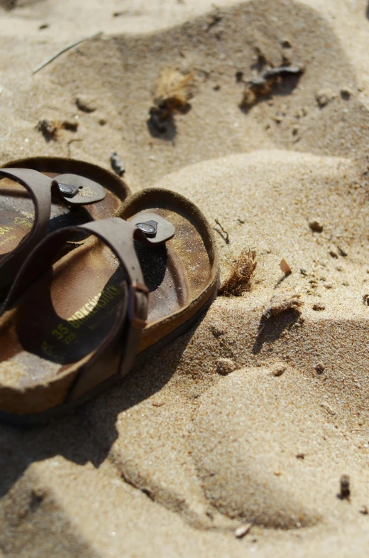 the brown sandals are left in the sand by the beach