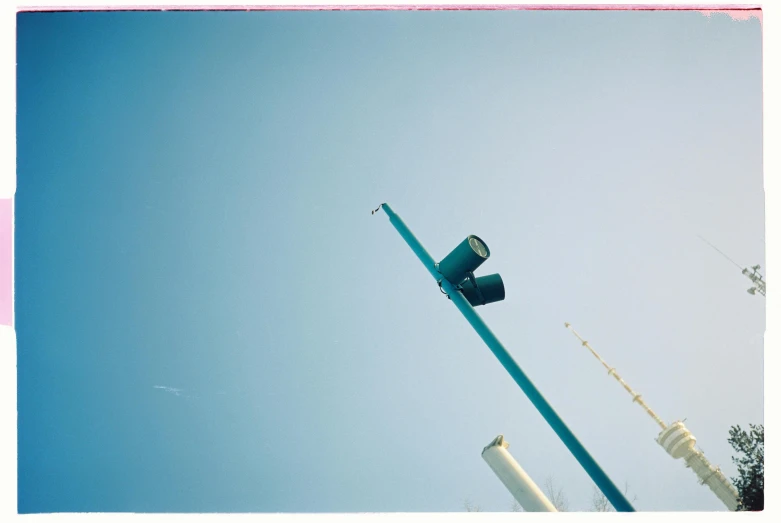 two traffic lights against a blue sky in front of poles
