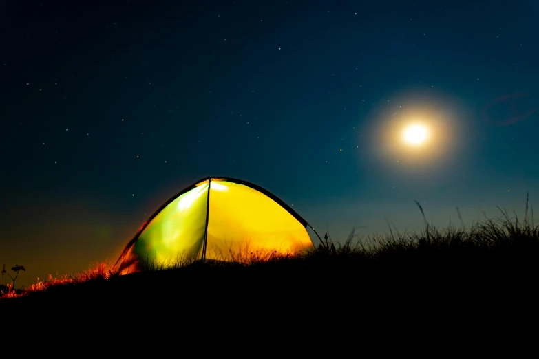 a tent in the dark with a bright yellow tent on top