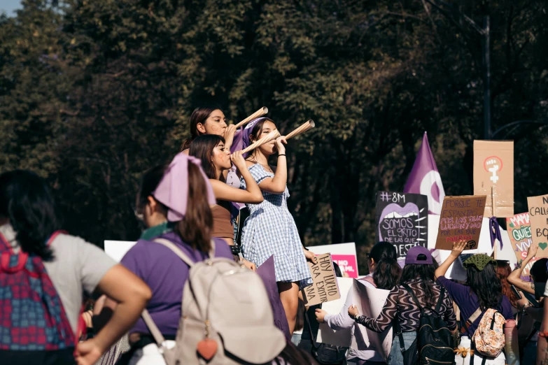 several women at a climate rally in the woods holding up signs