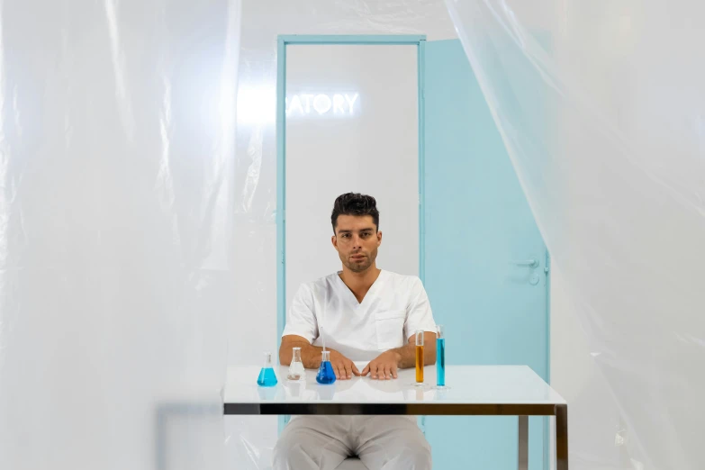 a man sits at a table with two bottles of liquid on it