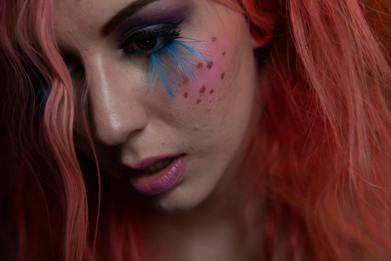 the young woman with bright pink hair has blue and pink makeup