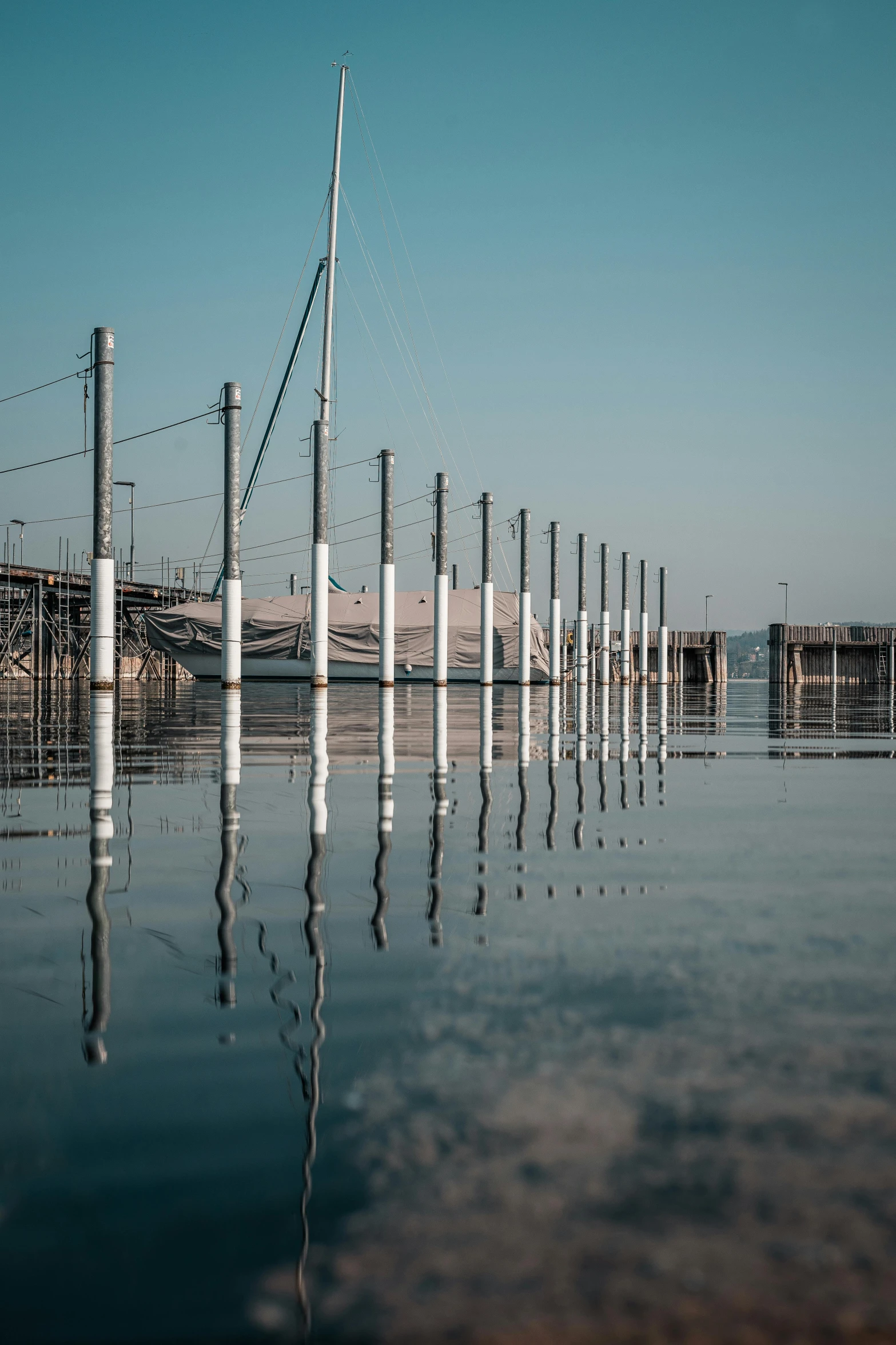 a row of poles in the water with some boats in the background