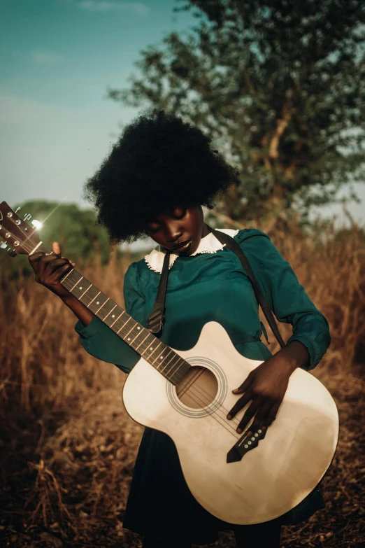 the person is playing an acoustic guitar in the field