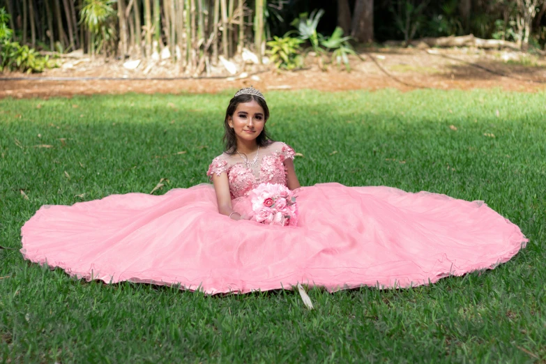 a little girl sitting on the ground in pink