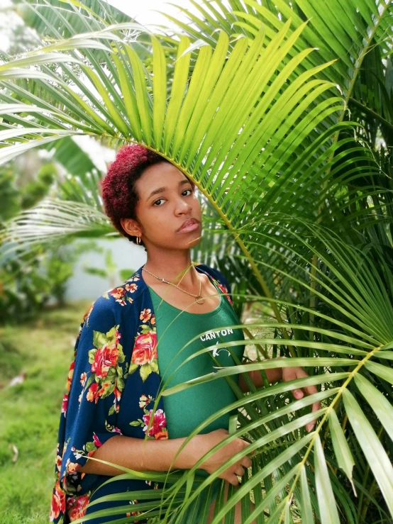 a woman with a red mohawk stands in front of a tree