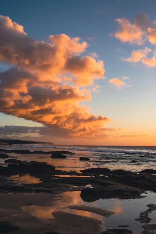 an image of sunset on the beach with clouds above