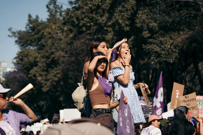 several people gathered in a park, one woman holding a baby and the other woman wearing purple