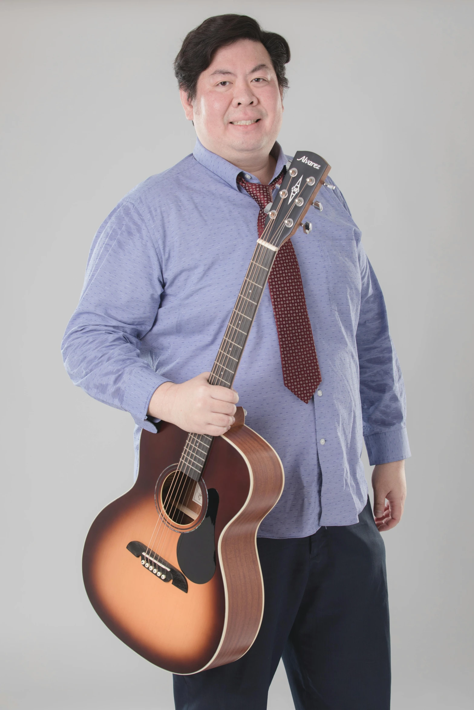 a person is holding a guitar and wearing a blue shirt