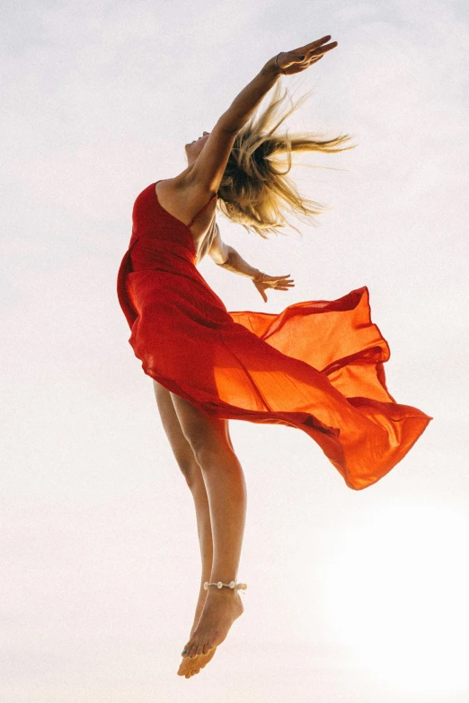 a girl in an orange dress jumps into the air