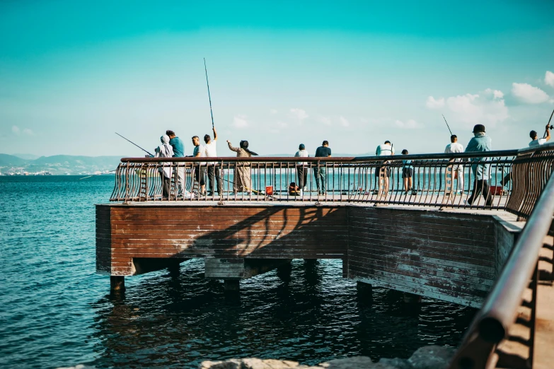 several people on a bridge fishing off of the side