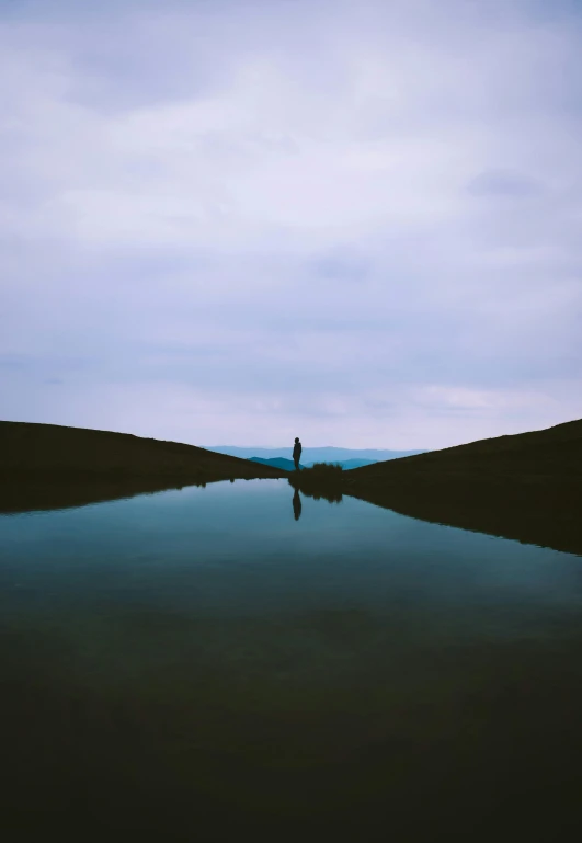 a lone person is on the water at dusk