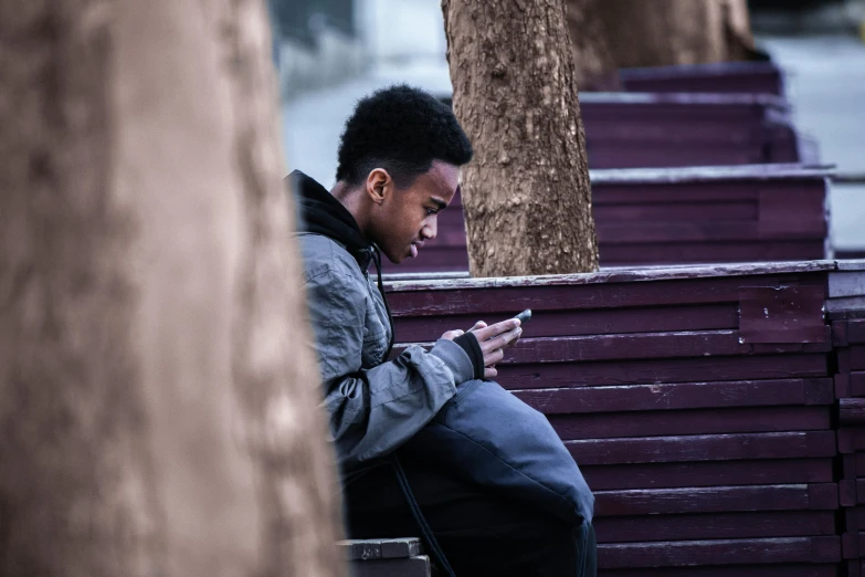 a man is sitting on a bench looking at his phone