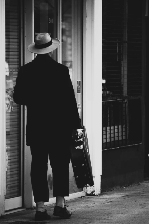 a man standing next to a closed door holding luggage