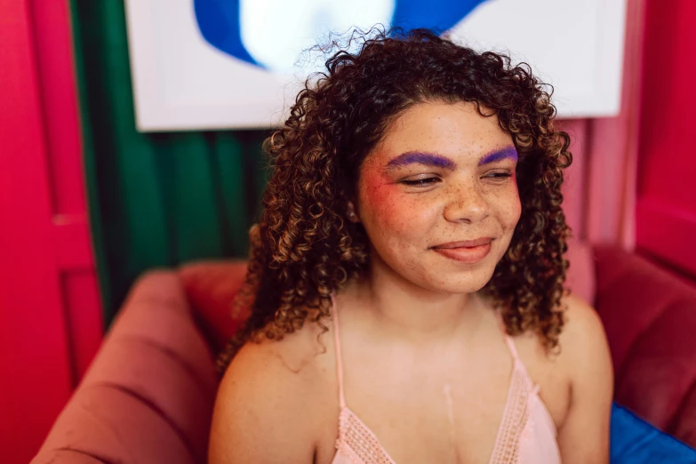 a young woman with painted face sits in a chair