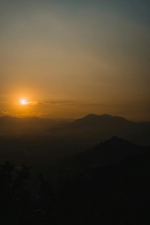 the sun rising over a valley in the distance