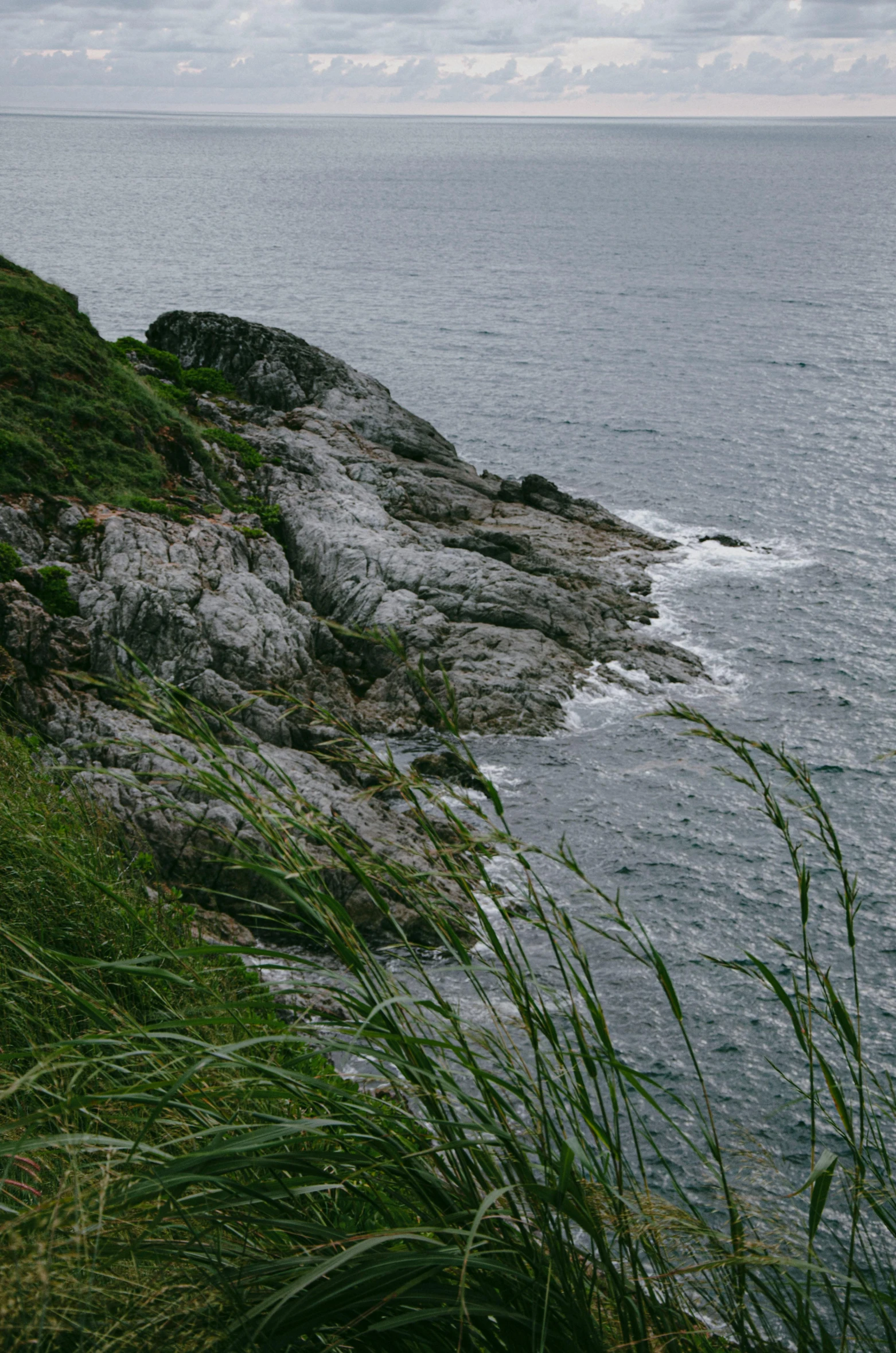 two people standing on top of a mountain next to the ocean