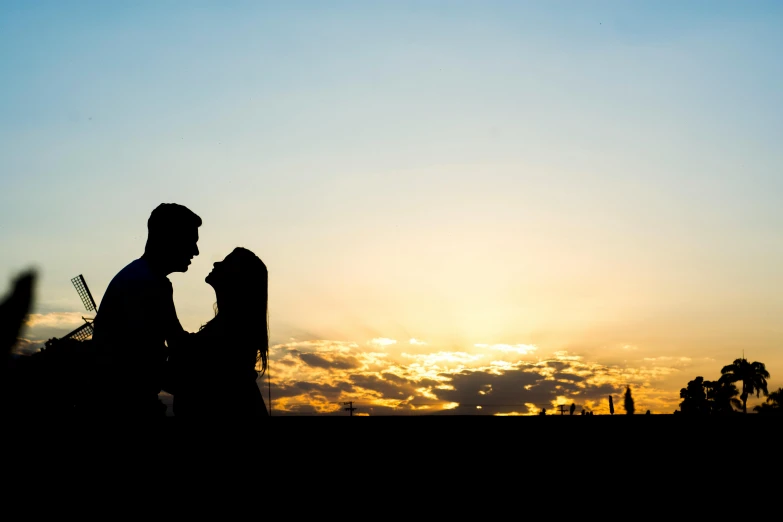 the silhouettes of two people who are in front of the sun