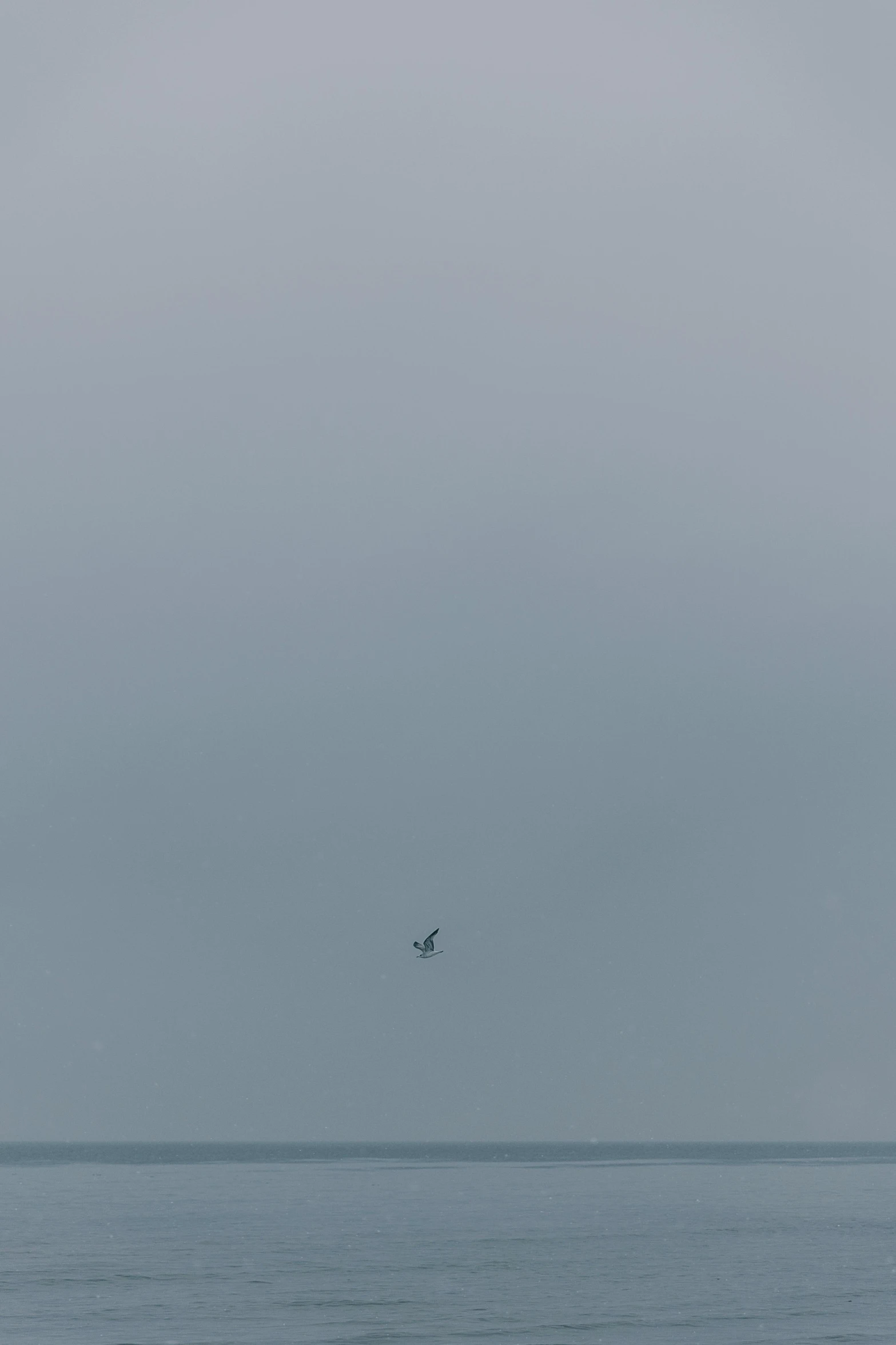 a lone airplane flying in the sky over water