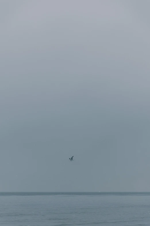 a lone airplane flying in the sky over water