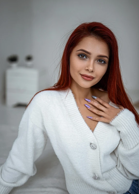 young woman with blue nails posing in front of a white bed