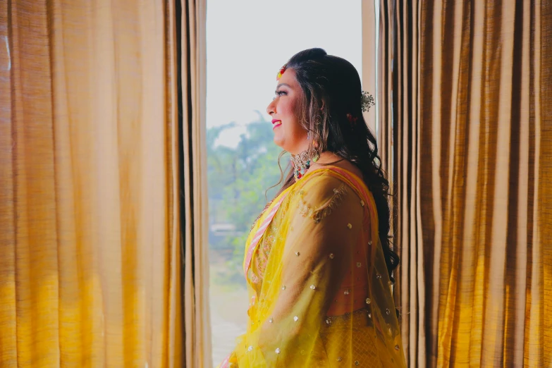 a woman standing near some curtains looking into a window