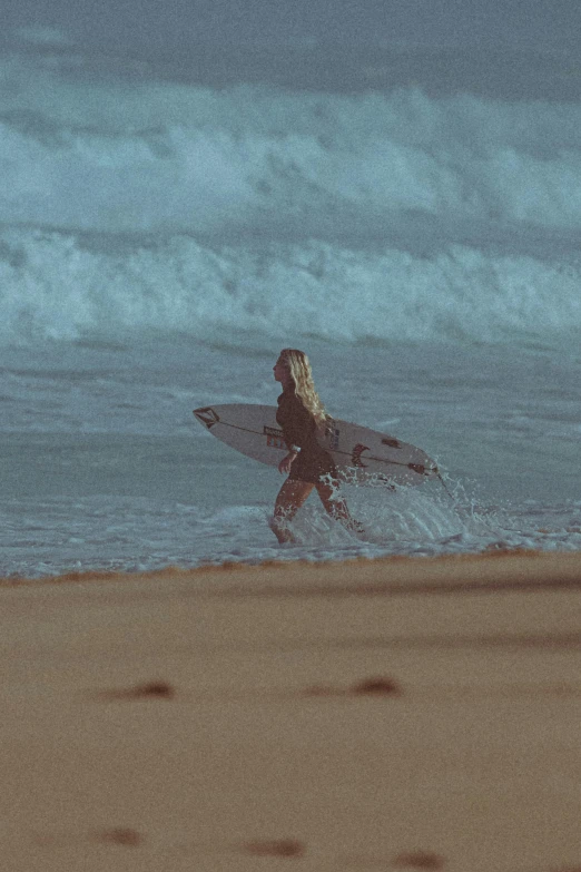a young woman with her surfboard running on the beach