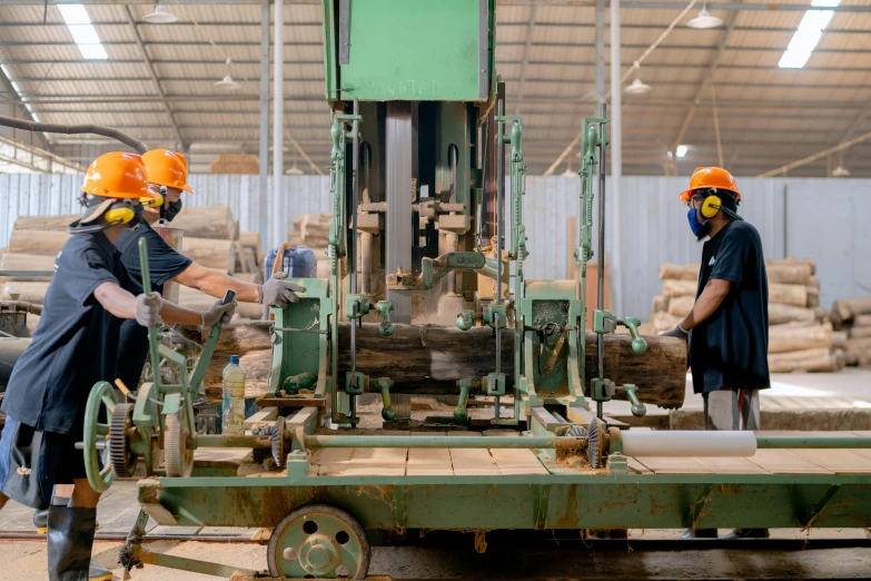 the two men wearing orange safety helmets are using machinery