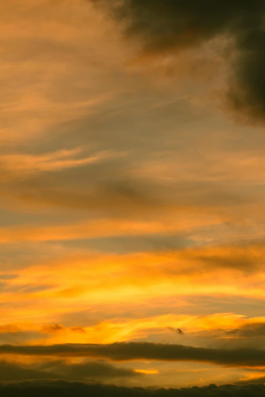 a plane flies through the cloudy sky at sunset