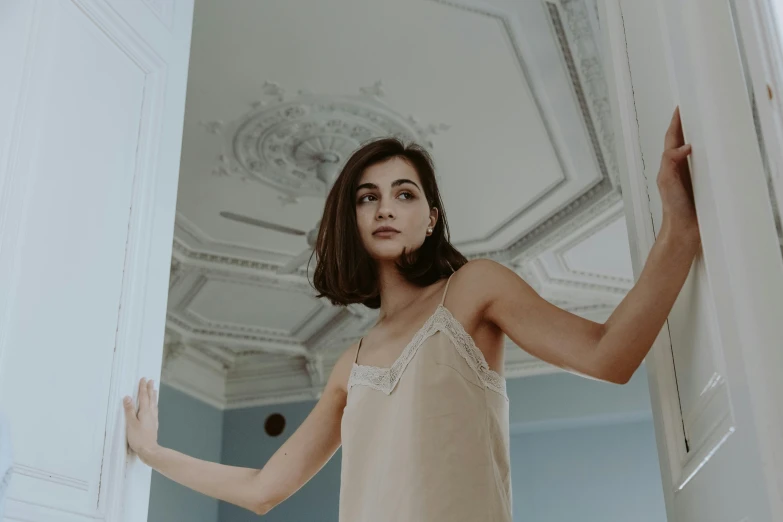 a woman is wearing a beige gown in a room