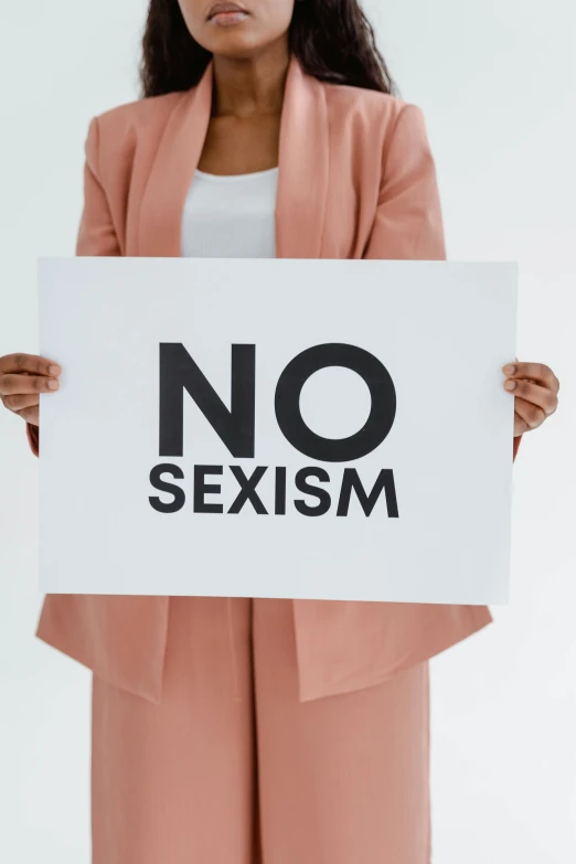 a person holding up a sign that says no sexism