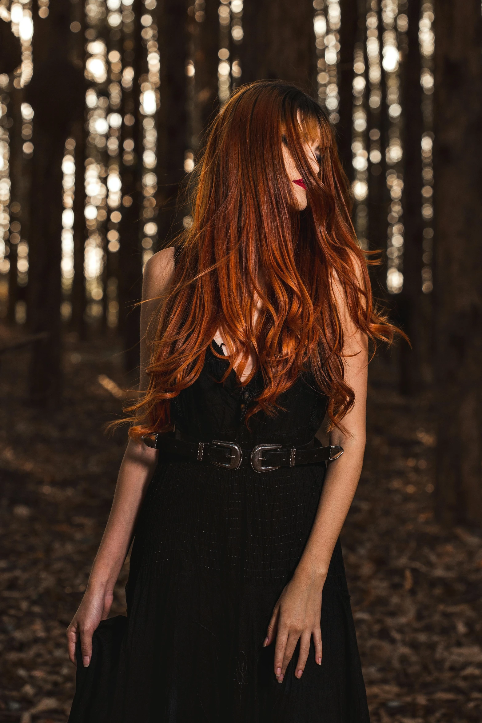 a woman with red hair and a black dress in a dark forest