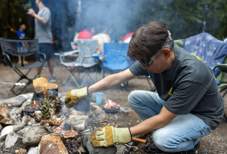 a man cooking food on an open fire outdoors