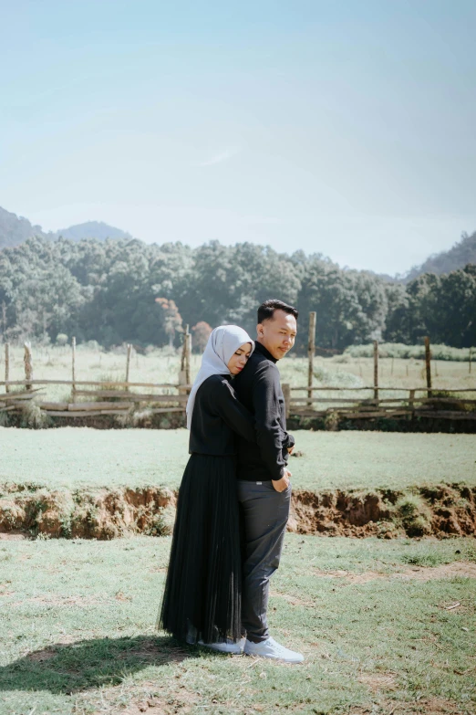 two people in formal wear standing together on the grass