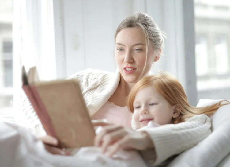 a woman reading to her child while sitting on the couch