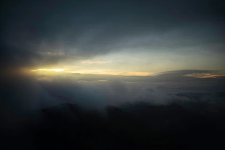 a sunset seen through dark clouds over mountains