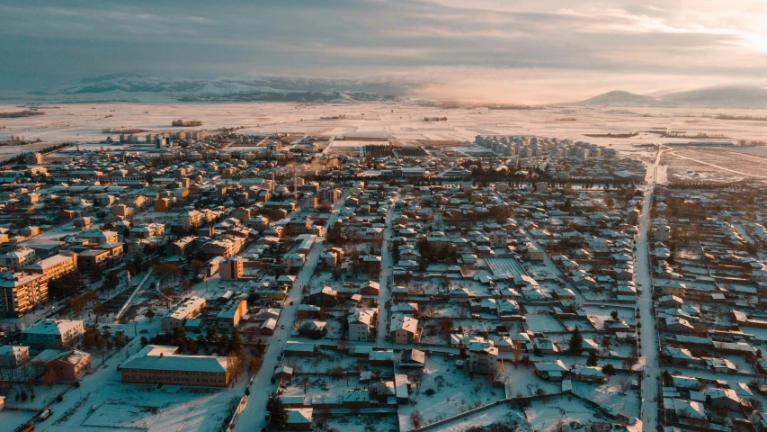 an aerial view of an urban area, looking across the snow covered landscape