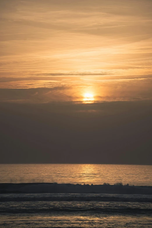 an ocean with the sun shining through a cloud