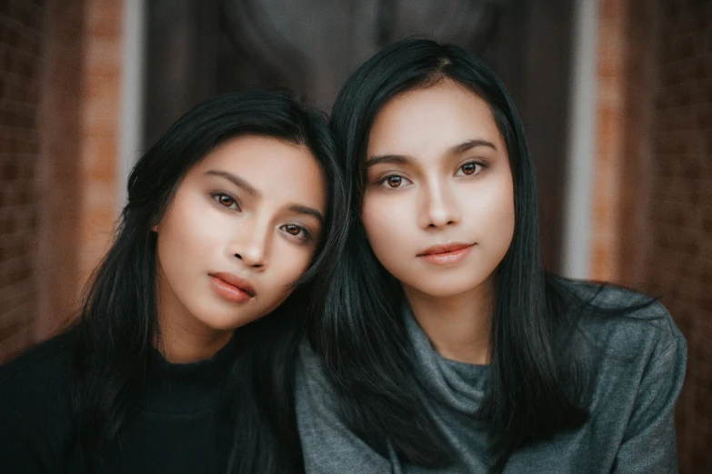 two women standing near each other and one holding a cell phone