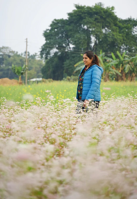 a woman in a blue coat standing in a field