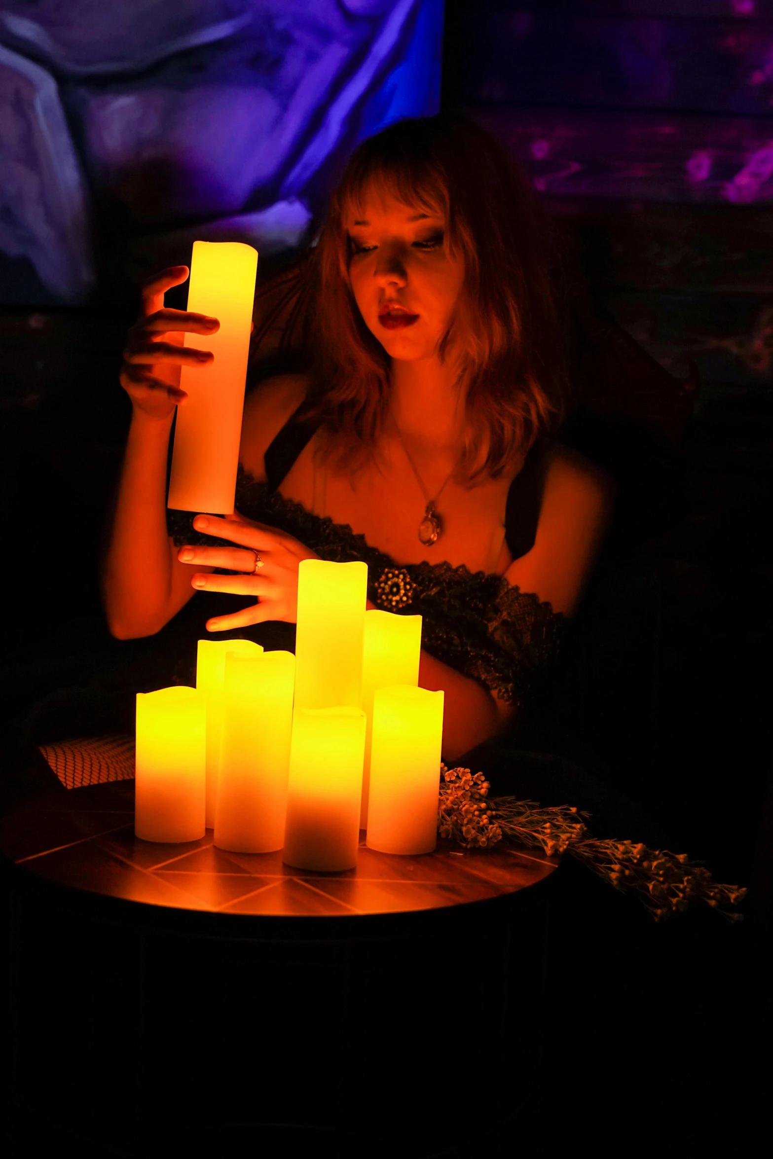 a woman holding up a candle surrounded by many lit candles